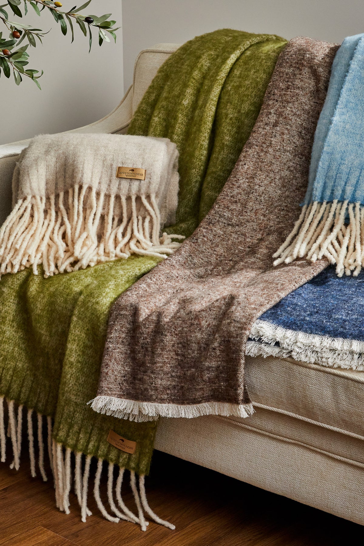 Andes and Cinder Mist throw in fern, mocha, truffle, ocean, and sky blue on a sofa