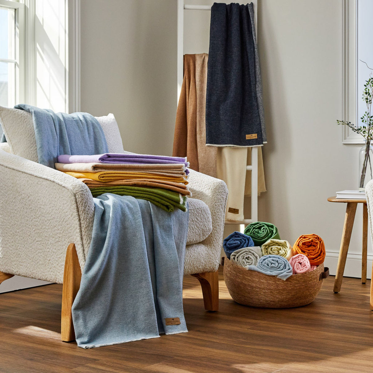 Andes solid throw blanket in assorted stacks on chair, basket, and blanket ladder