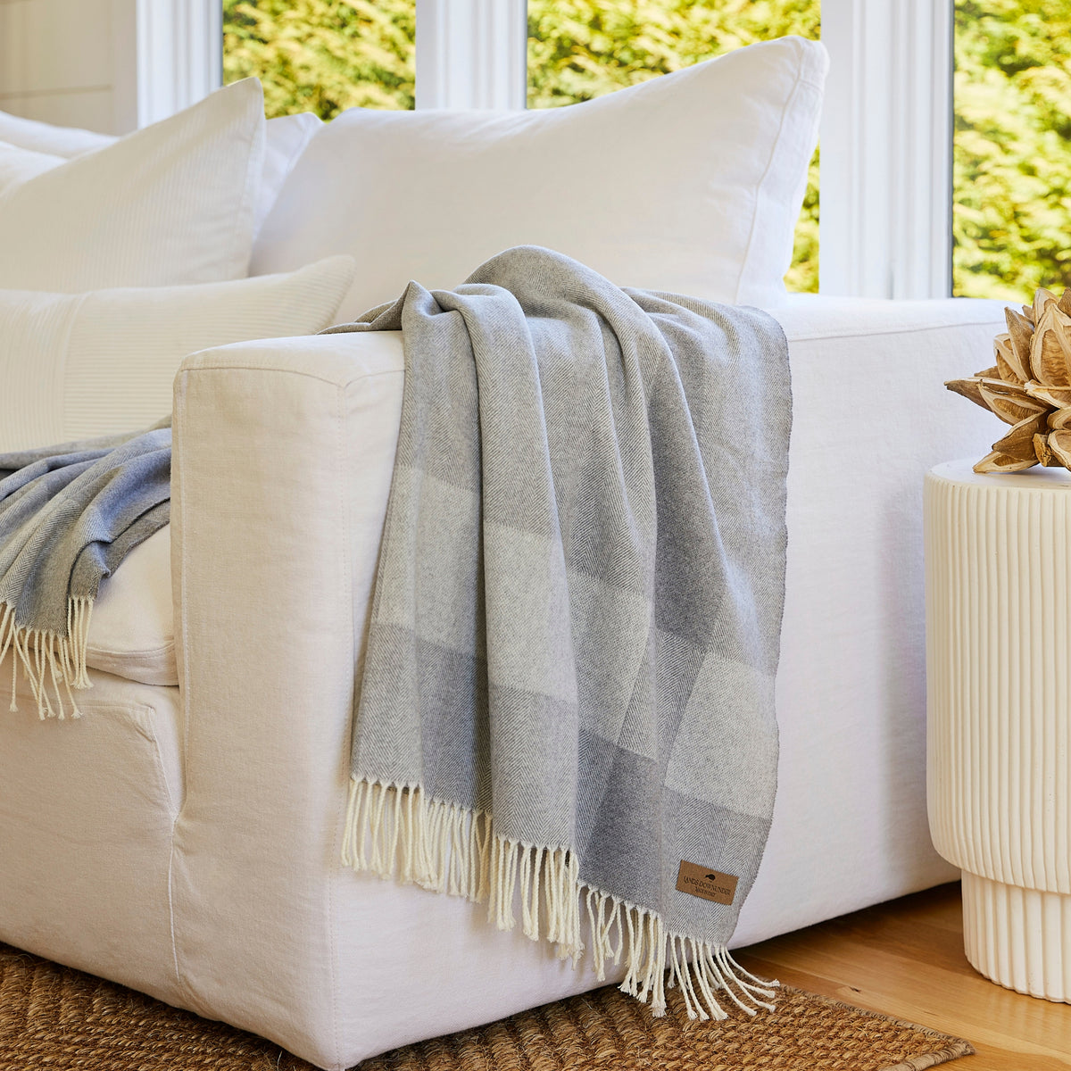 hampton plaid herringbone throw blanket in silver on a white couch