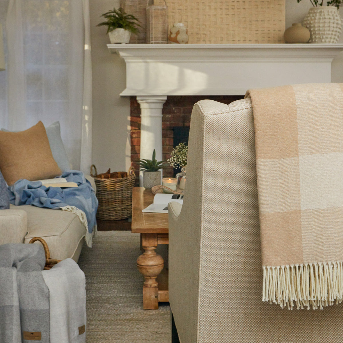 hampton plaid throw blankets in dune, chambray, and silver draped around a cozy living room